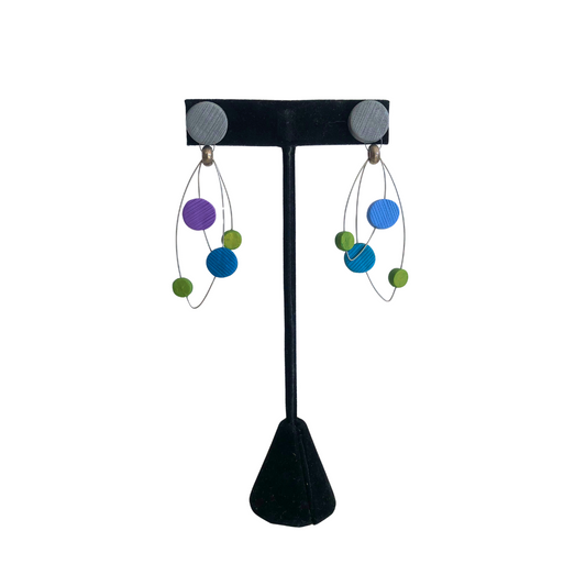 Pair of earrings on a black earring stand with colorful beads.